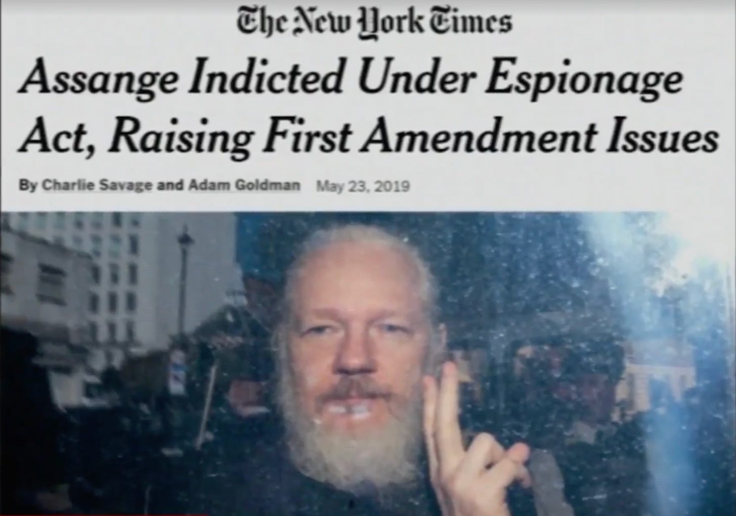 A New York Times headline, "Assange Indicted Under Espionage Act, Raising First Amendment Issues" appears over a picture of a bearded Julian Assange holding up two fingers.