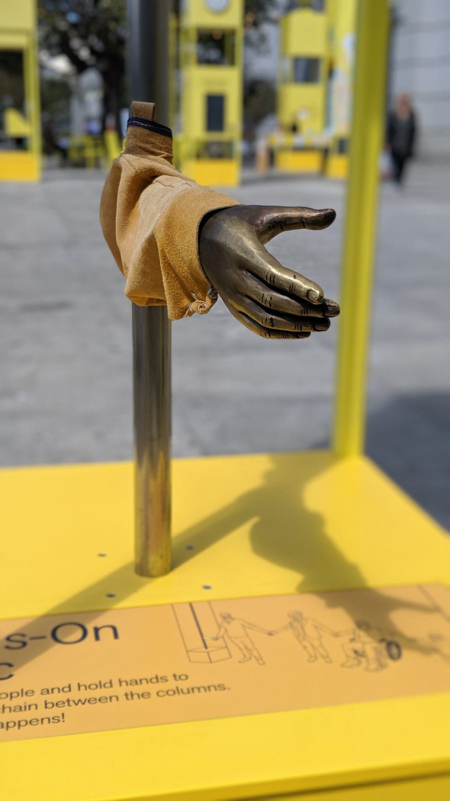 A sculpted brass arm extends its hand as if for a handshake.