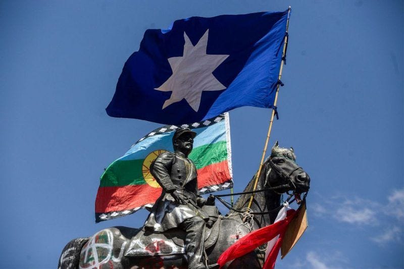 Mapuche flags are pictured on top of a sculpture of Chilean former army commander in chief Manuel Baquedano during a protest in Santiago, Chile, on Oct. 26, a day after more than one million people took to the streets for the largest protests in a week of demonstrations. (Claudio Reyes/AFP/Getty Images)