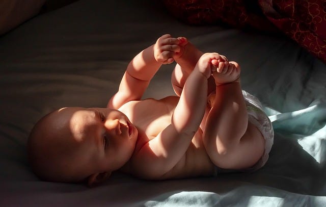 A baby plays with her toes