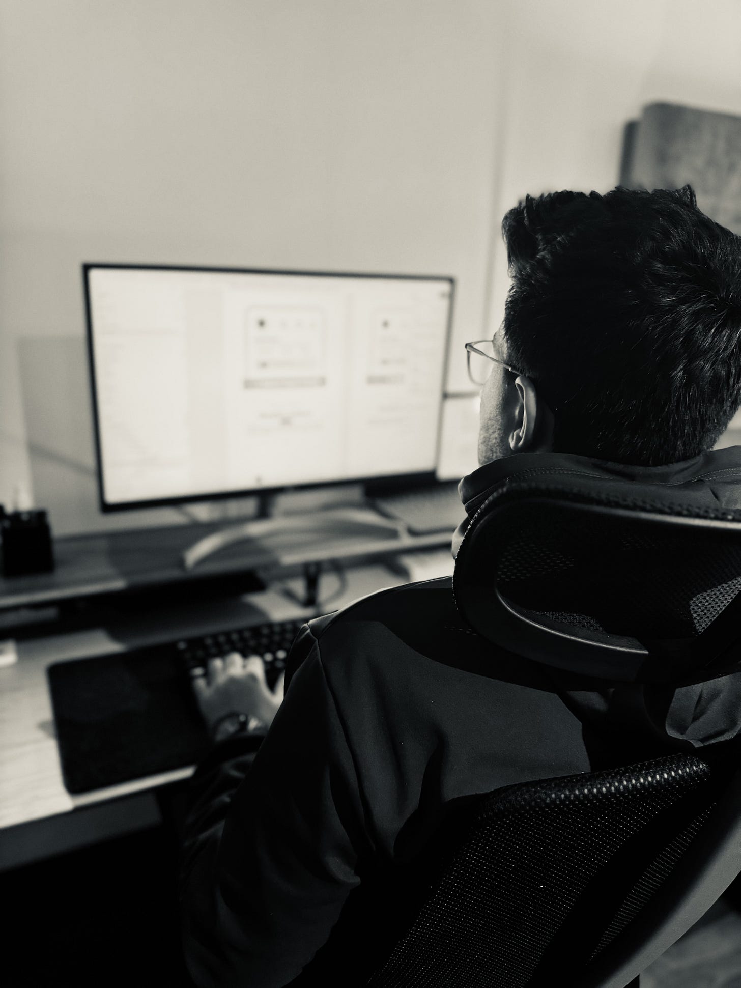 black and white photo of a man sitting at a computer