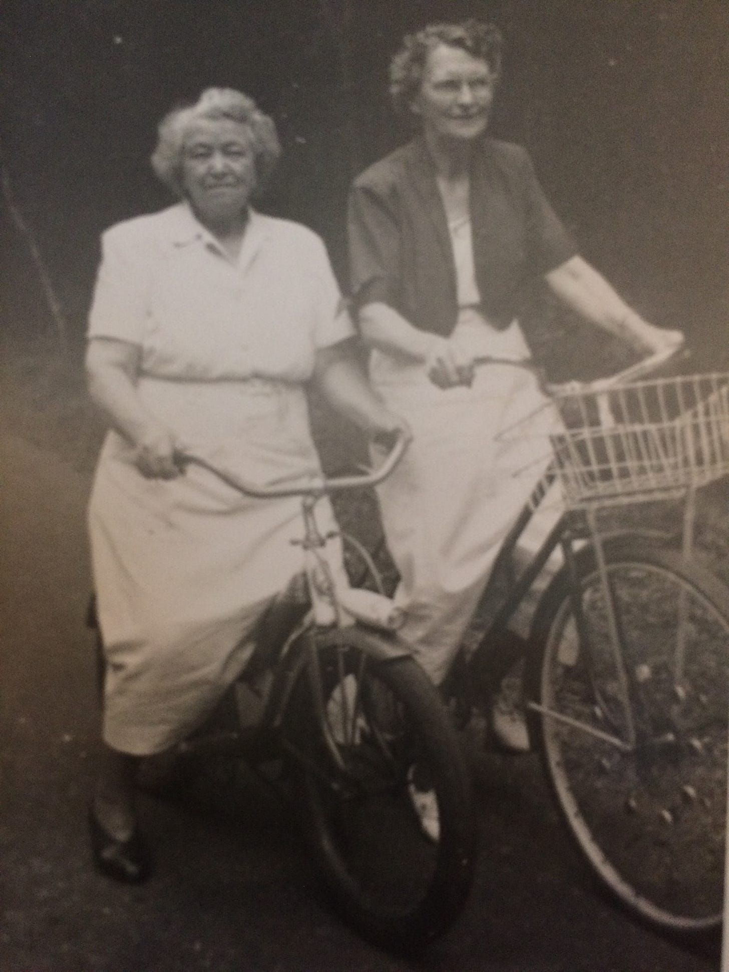 Black and white photo of two women on bikes