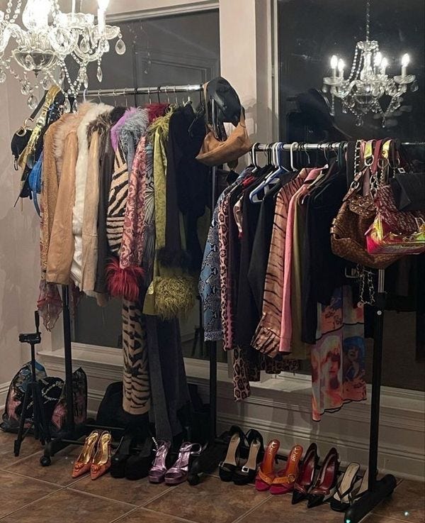 This may contain: clothes and shoes are hanging on racks in front of a window with chandelier