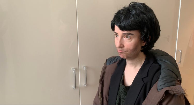 photo of Susan dressed up as a man, in a short black wig, with stubble and a big winter coat