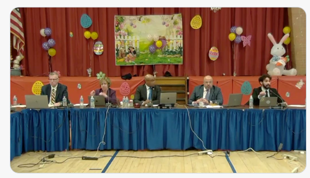 Picture of several of the JCBOE members at a table, surrounded by Easter decorations, including a large inflatable rabbit and several eggs. It's weird.