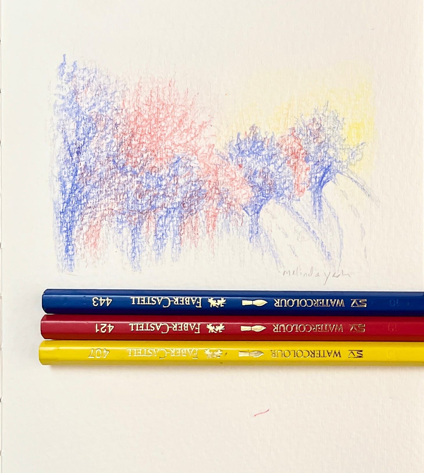 image: close up from a sketchbook of colour pencil drawing of trees in blue and red, with a tinge of yellow for the sunset, the colour pencils are laid up neatly in a row of three as props