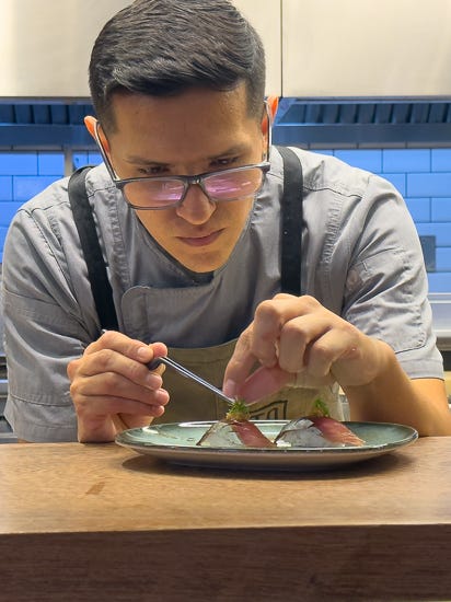 Chef at Tomo puts on the finishing garnishes on a plate of nigiri before sending it out to eager diners.