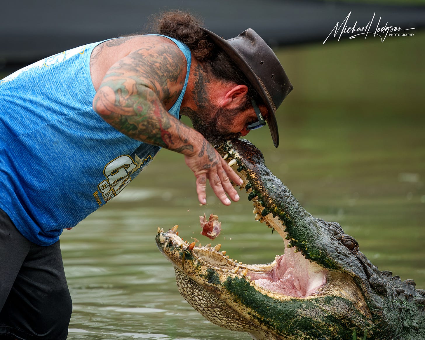 Arlie Hammonds kissing an alligator, Big Al, on the nose as he feeds him. 