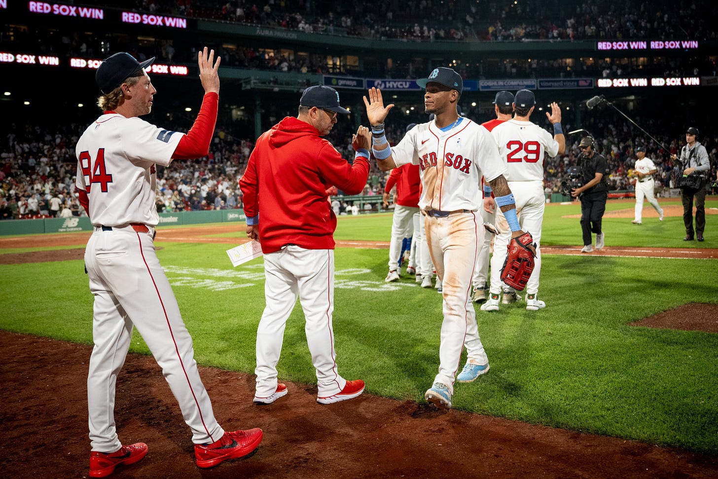 Ceddanne Rafaela walks along the high-five line following the win at Fenway Park. He high-fives Ramon Vazquez and Kyle Hudson. 