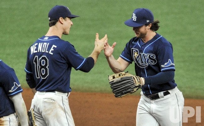 Picture of Joey Wendle and Brett Phillips, both white baseball players in their Tampa Bay Rays uniforms, giving a high five after the Rays beat the Phillies at a 2020 game