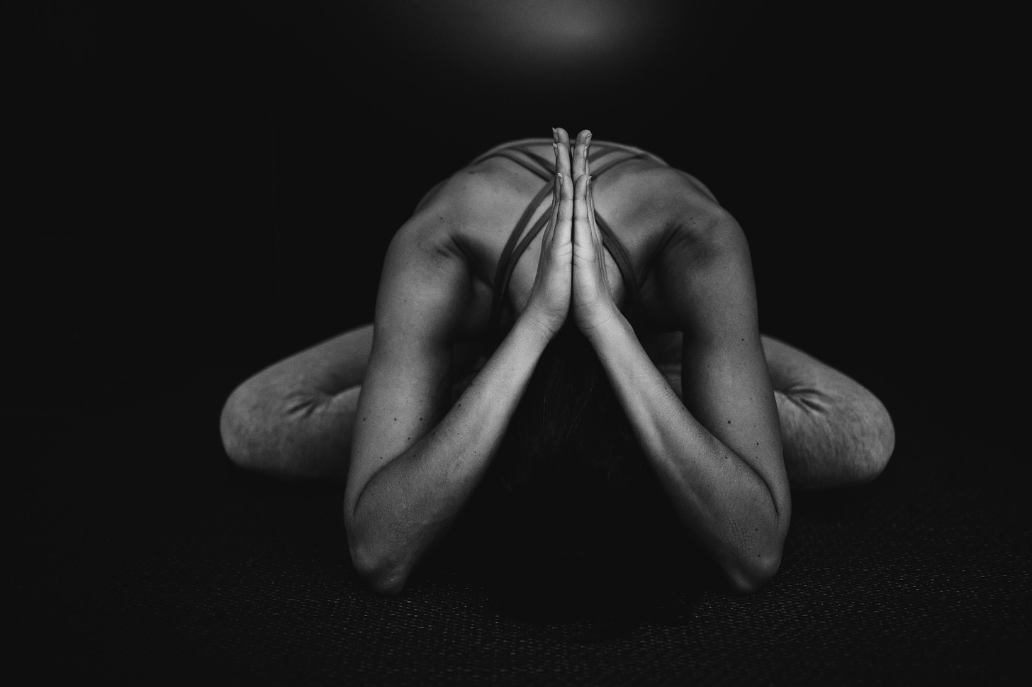 una donna in posizione yoga con mani giunte fotografata in bianco e nero