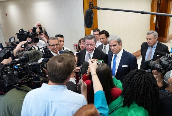 Dan Cogdell, defense attorney for suspended Attorney General Ken Paxton, speaks to reporters at the Harris County Courthouse in Houston last month. A boom mic hangs over his head, and reporters point television cameras at him. 