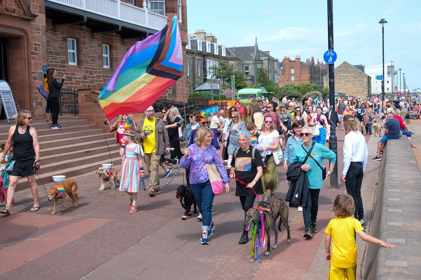 Group of Pride marchers with rainbow flags and lots of dogs on Portobello Promenade
