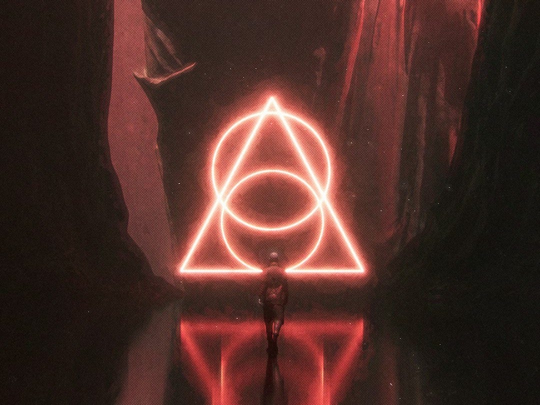 a person standing in a dark tunnel with a neon triangle