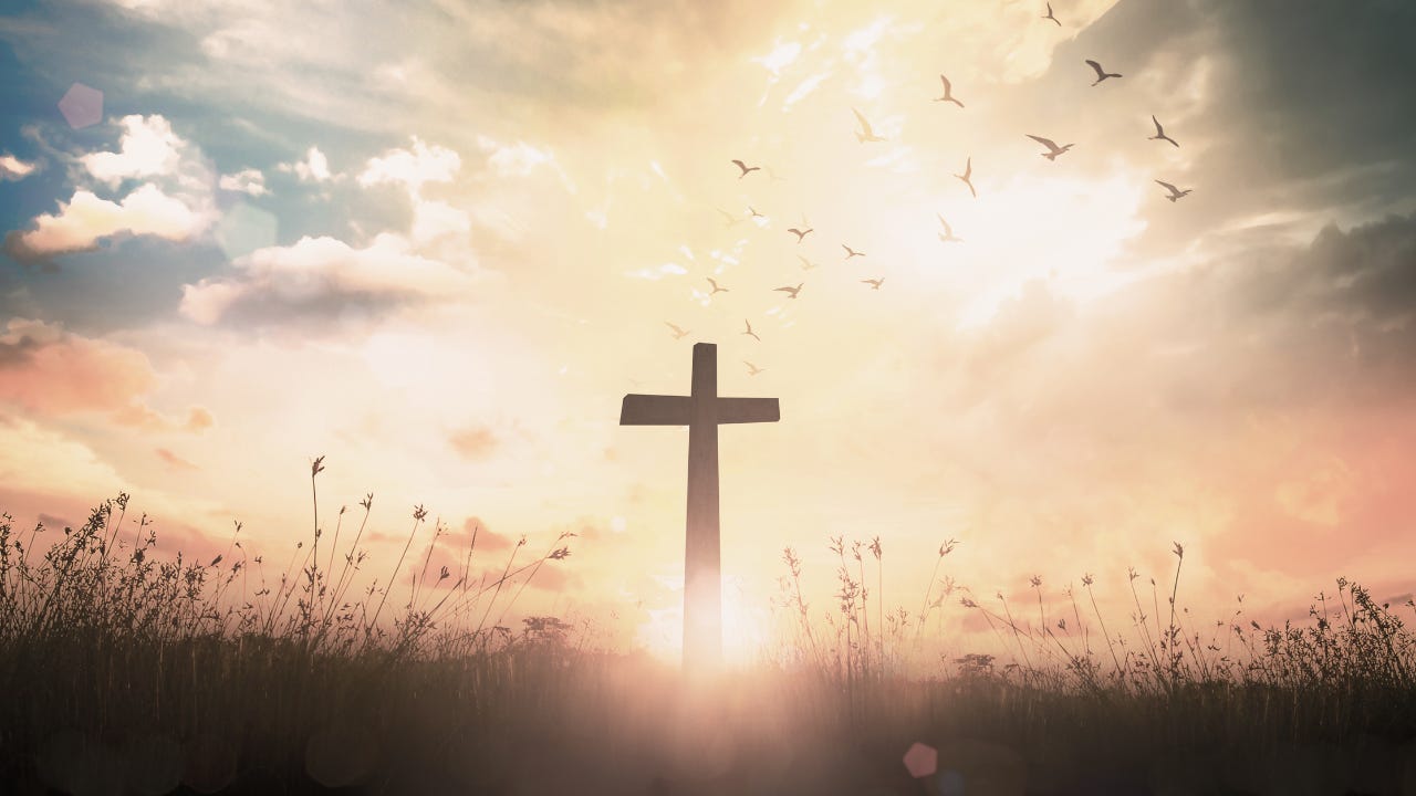 A cross in front of the sun in a field.