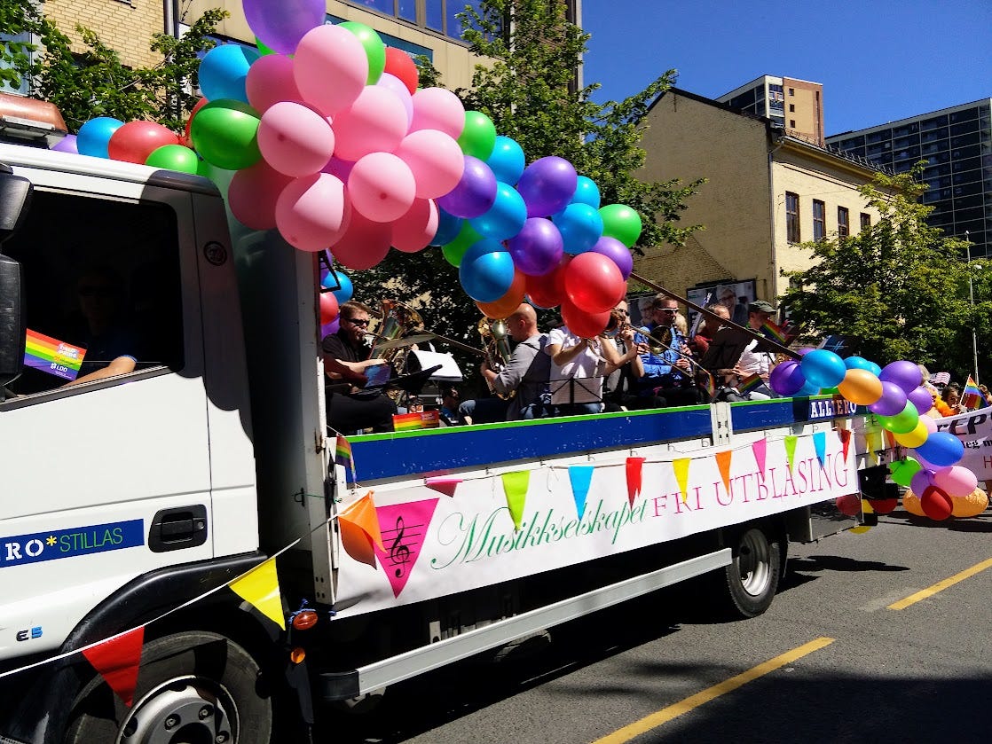 A parade float covered with swags of balloons in a rainbow gradient.