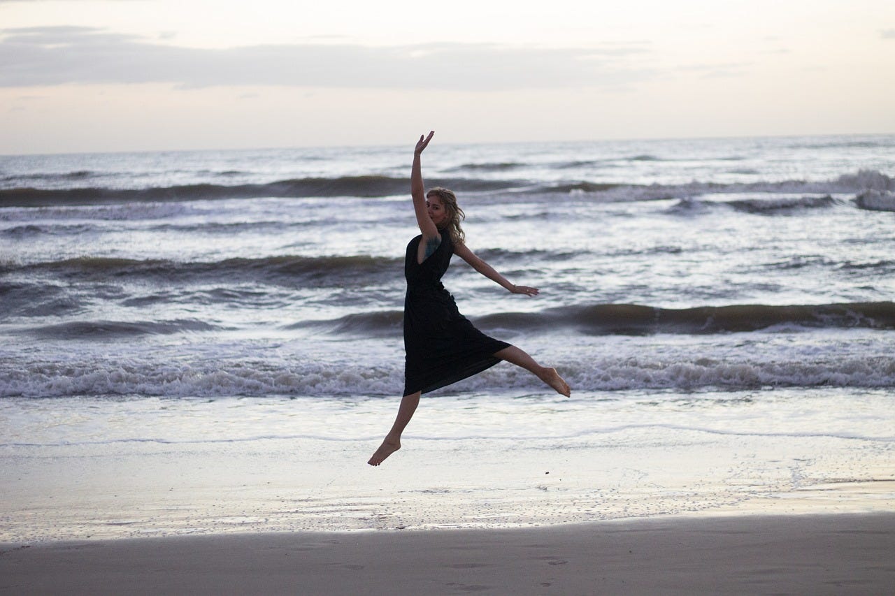 Woman dancing on beach near ocean