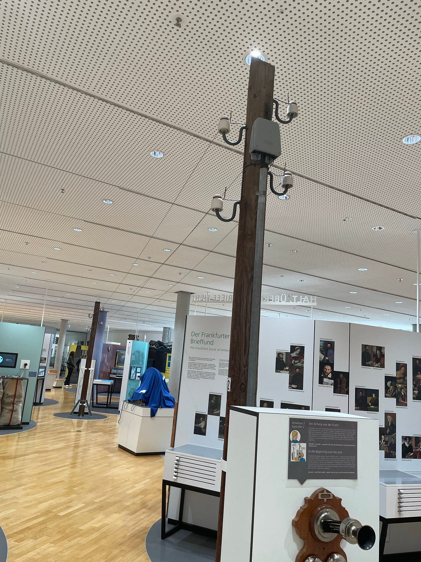 two telephone poles with functional box, lines running between them, ceramic insulators. inside a museum setting with a drop ceiling