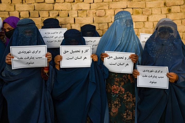 Afghan burqa-clad women hold placards as they protest for their right to education, in Mazar-i-Sharif on August 12, 2023.