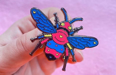 an an enamel pin in the shape of a honey bee with polyamorous pride colors