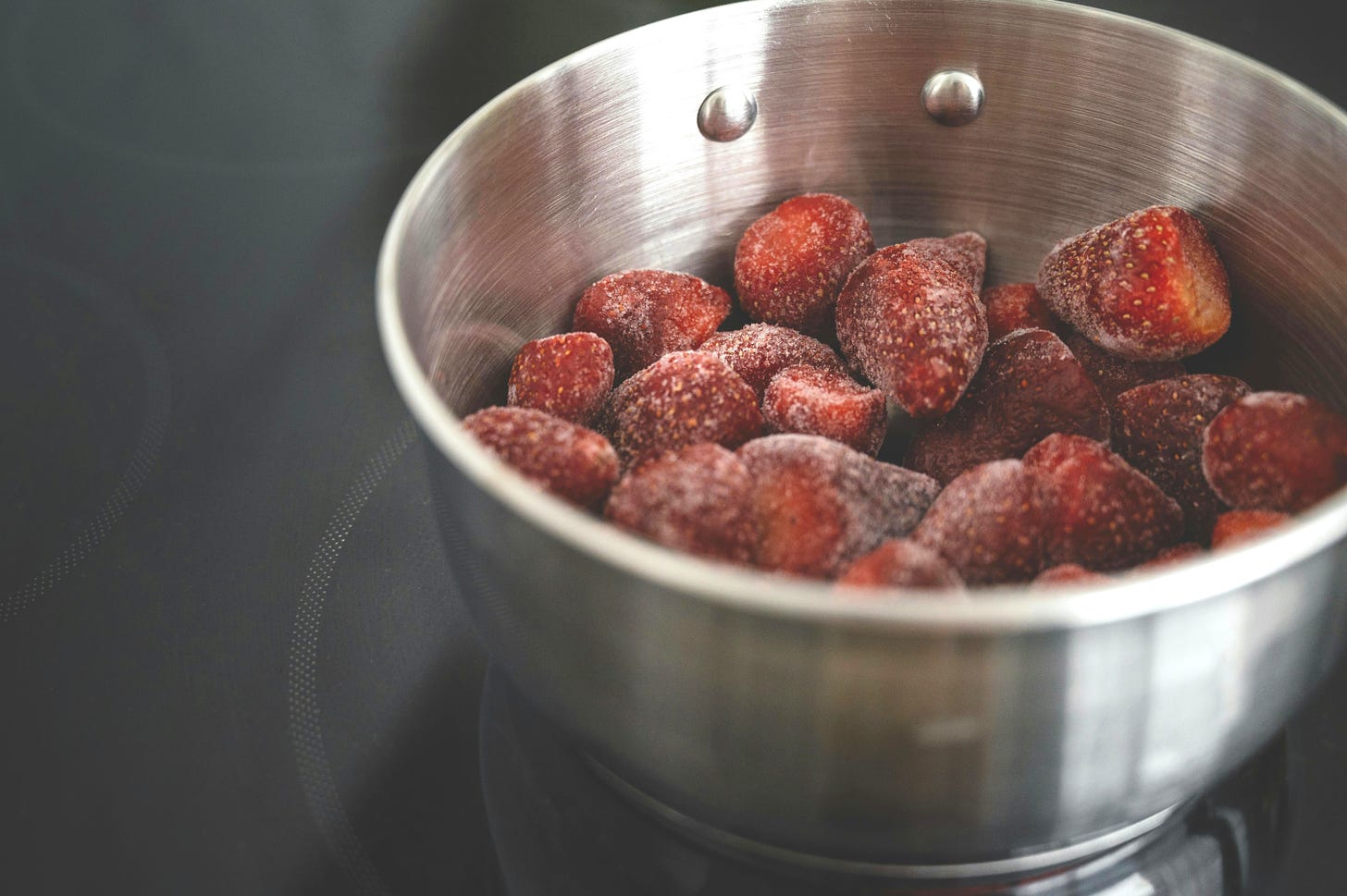 frozen strawberries in stainless steel pan on induction hob