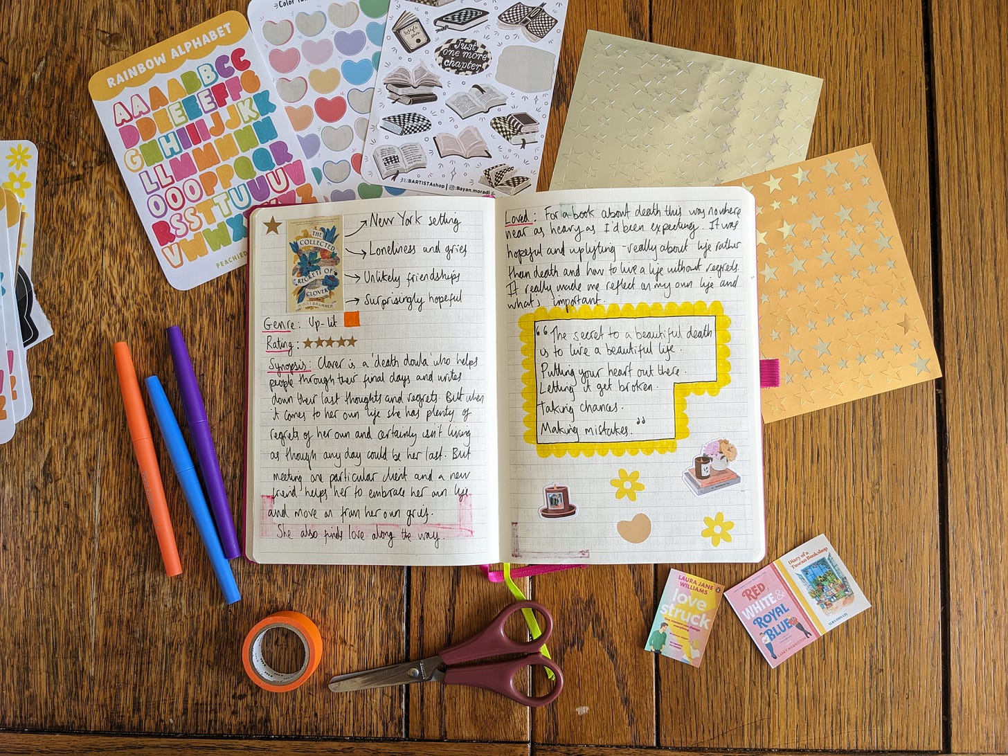 A notebook is open on a table, surrounded by stickers and pens.