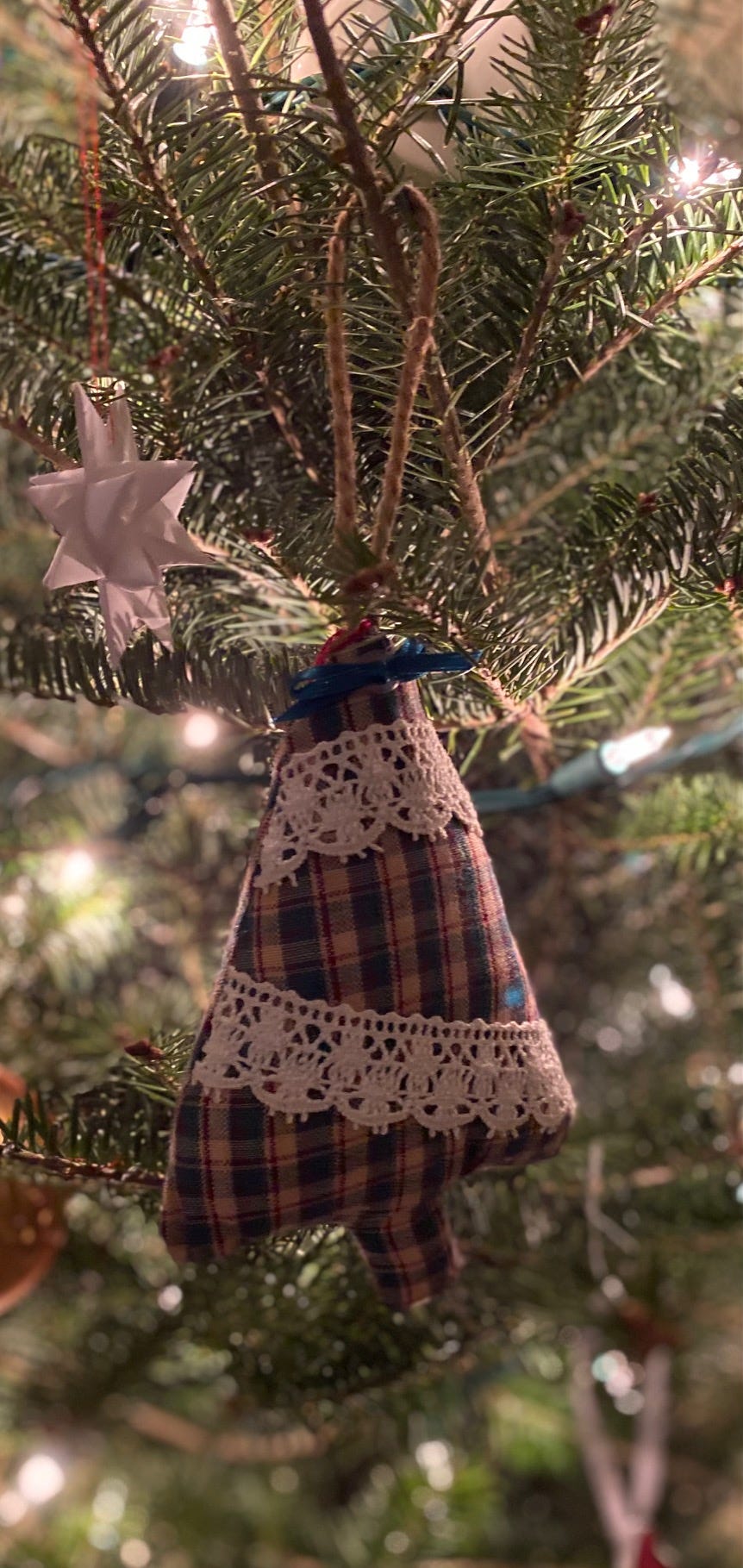 Handmade ornament hanging on tree. Fabric tree, lightly stuffed, in green and read plaid pattern with lace sewn on for garland.
