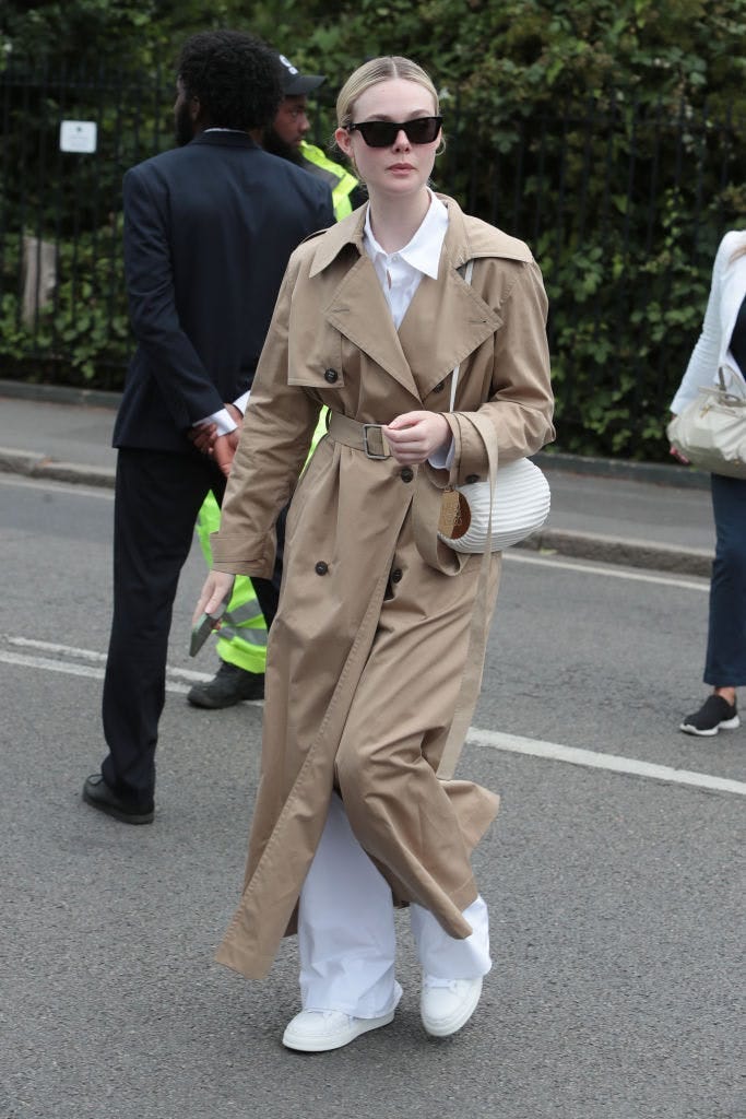 Elle Fanning in a brown trench coat and white pants.