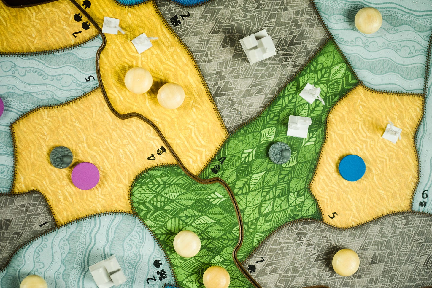 The board game Spirit Island. There are invader figures in multiple desert tiles, and cities are present in several places on the board.