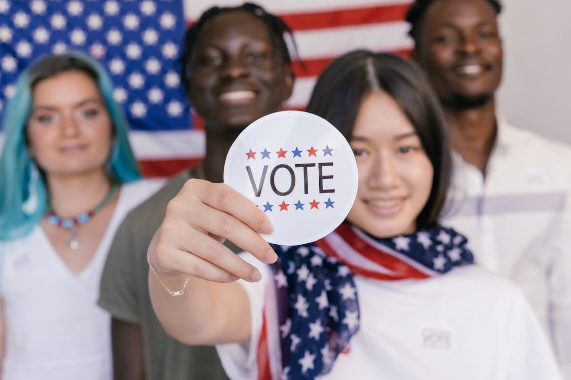 Free Group of diverse young adults promoting voting with a focus on a 'VOTE' sticker. Stock Photo