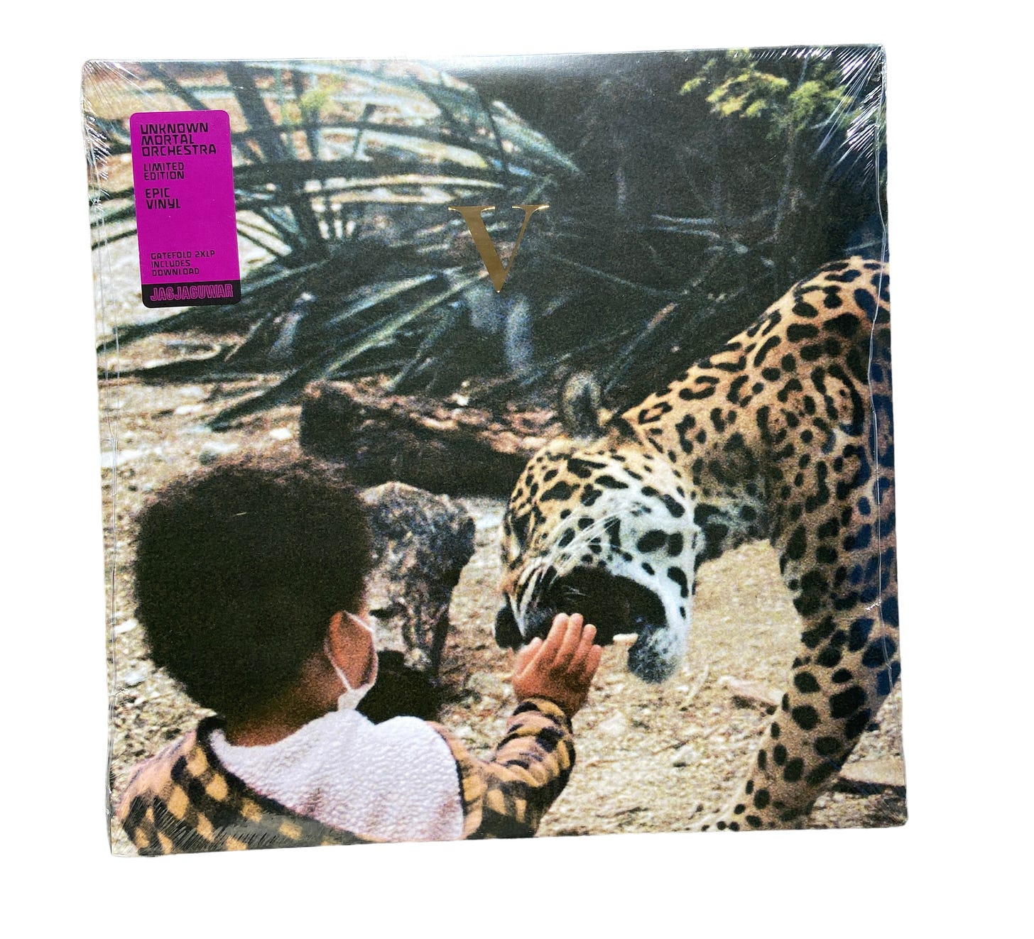 the vinyl for Unknown Mortal Orchestra's album V, still in its plastic wrap. A small child wearing a face mask reaches their hand towards a jaguar.