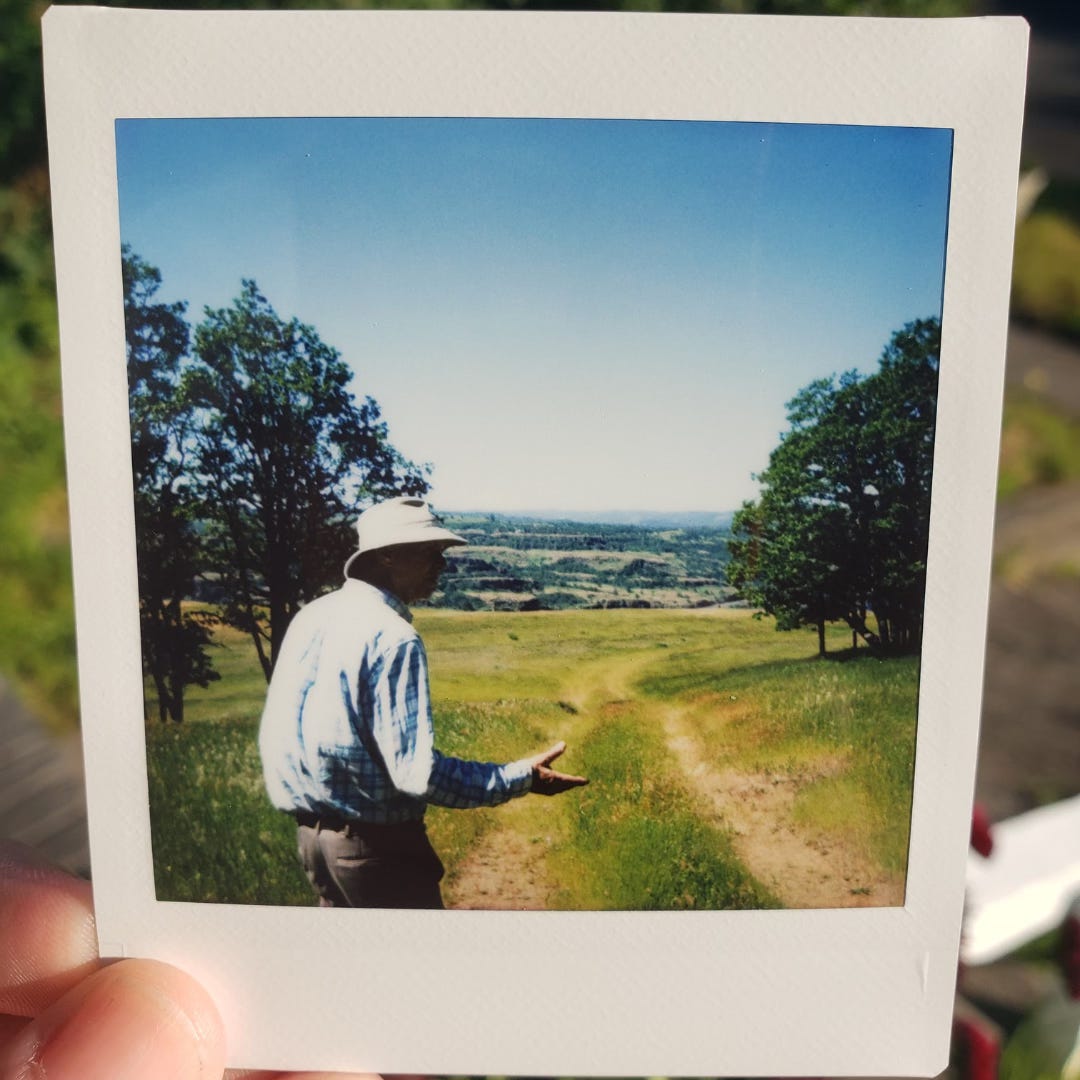 A man walks and talks along a hiking path, his right hand outstretched