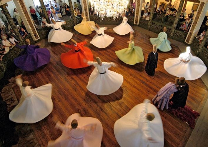 image: whirling dervishes of the Mevlevi sect in colorful dress performing a circle dance in an indoor space