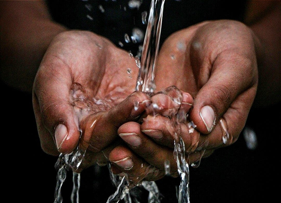 pouring water on person's hands