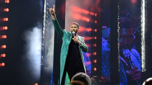 A photo depicts Usher performing on stage