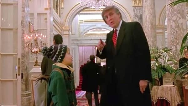A 10 year old white boy in a green jacket and knit hat stands across from a middle aged Donald Trump, a tall blonde man with a bad combover and a suit. They are in the opulent lobby of the Plaza Hotel.