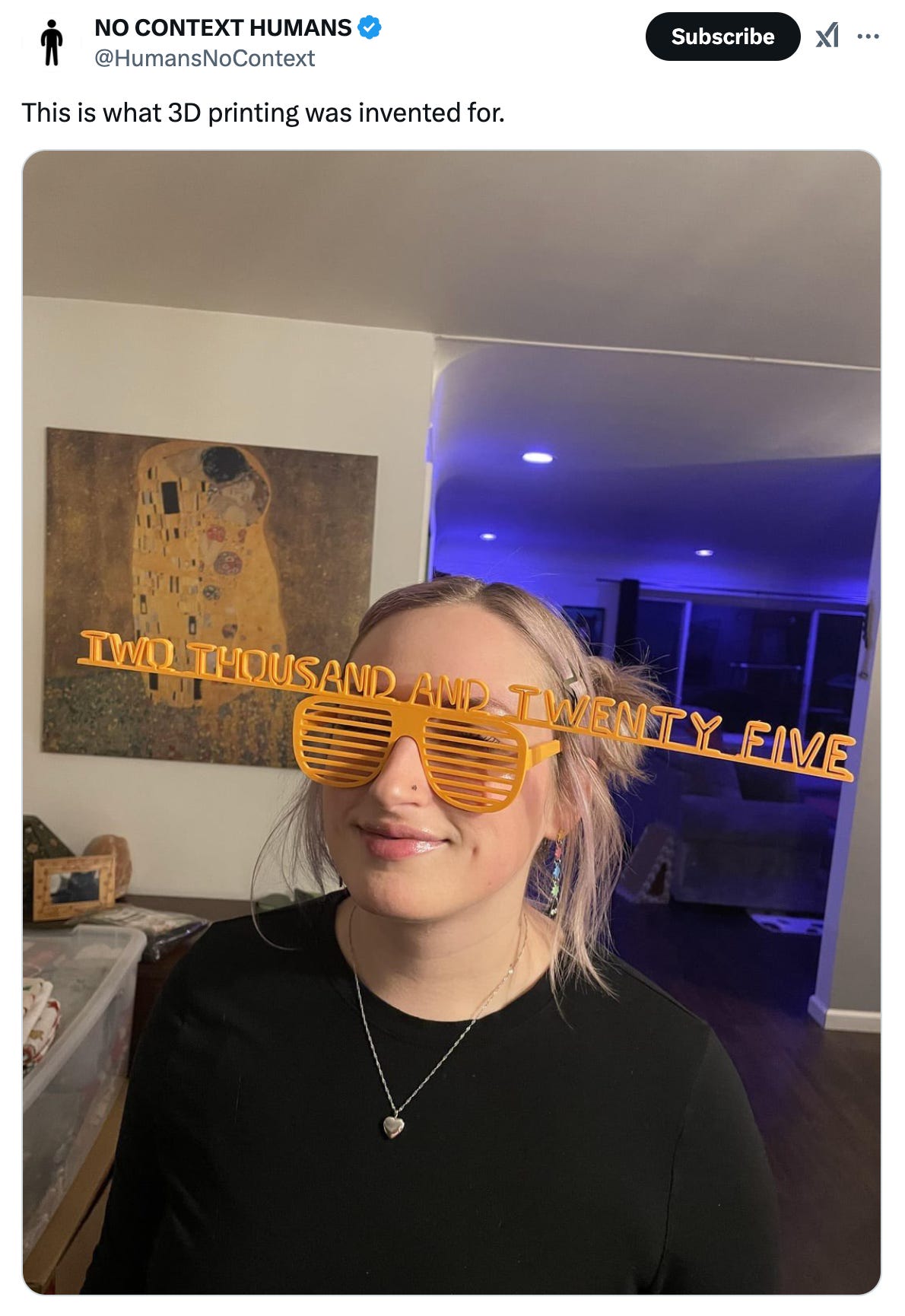 A tweet from @humansnocontext featuring an image of a woman wearing a pair of 3D printed glasses that say two thousand and twenty five across the top and it's about 2 feet long