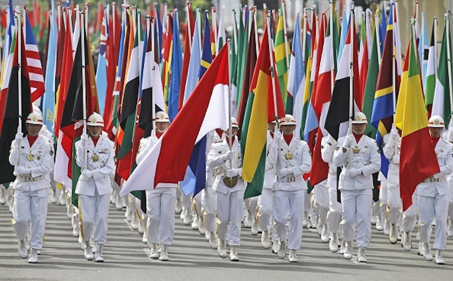 Soldiers lead an honour guard carrying numerous flags of countries from the global South.