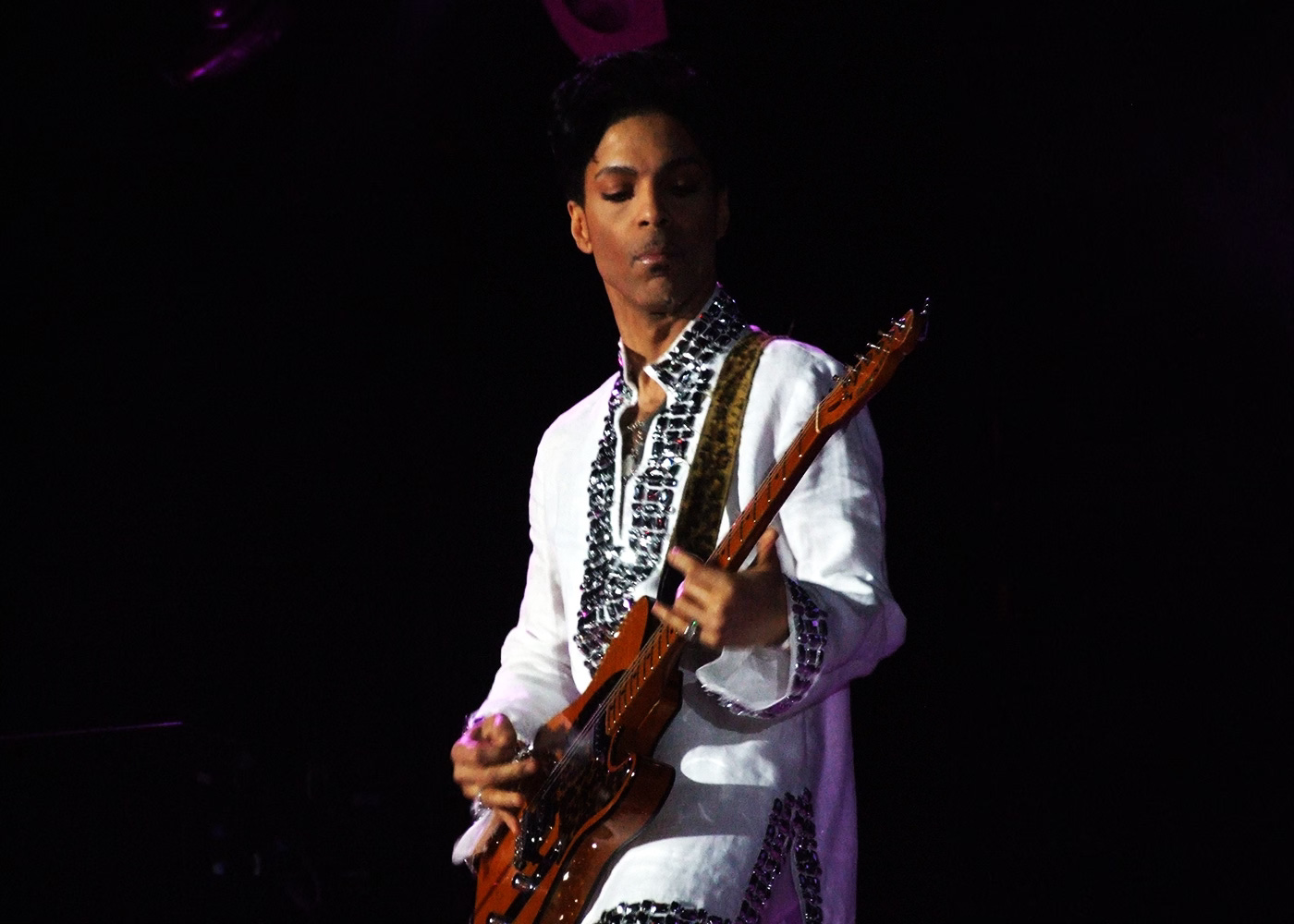 Prince, wearing a white kaftan, playing guitar live on stage at the Coachella Festival in 2008