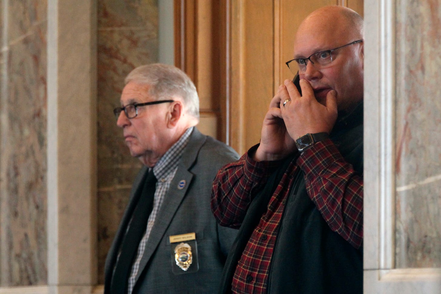 Kansas Republican Party Chairman Mike Brown, right, watches and works on his cell phone from the floor of the Kansas House.