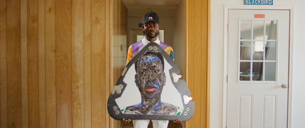 Amoako Boafo holding the portrait of his mother.