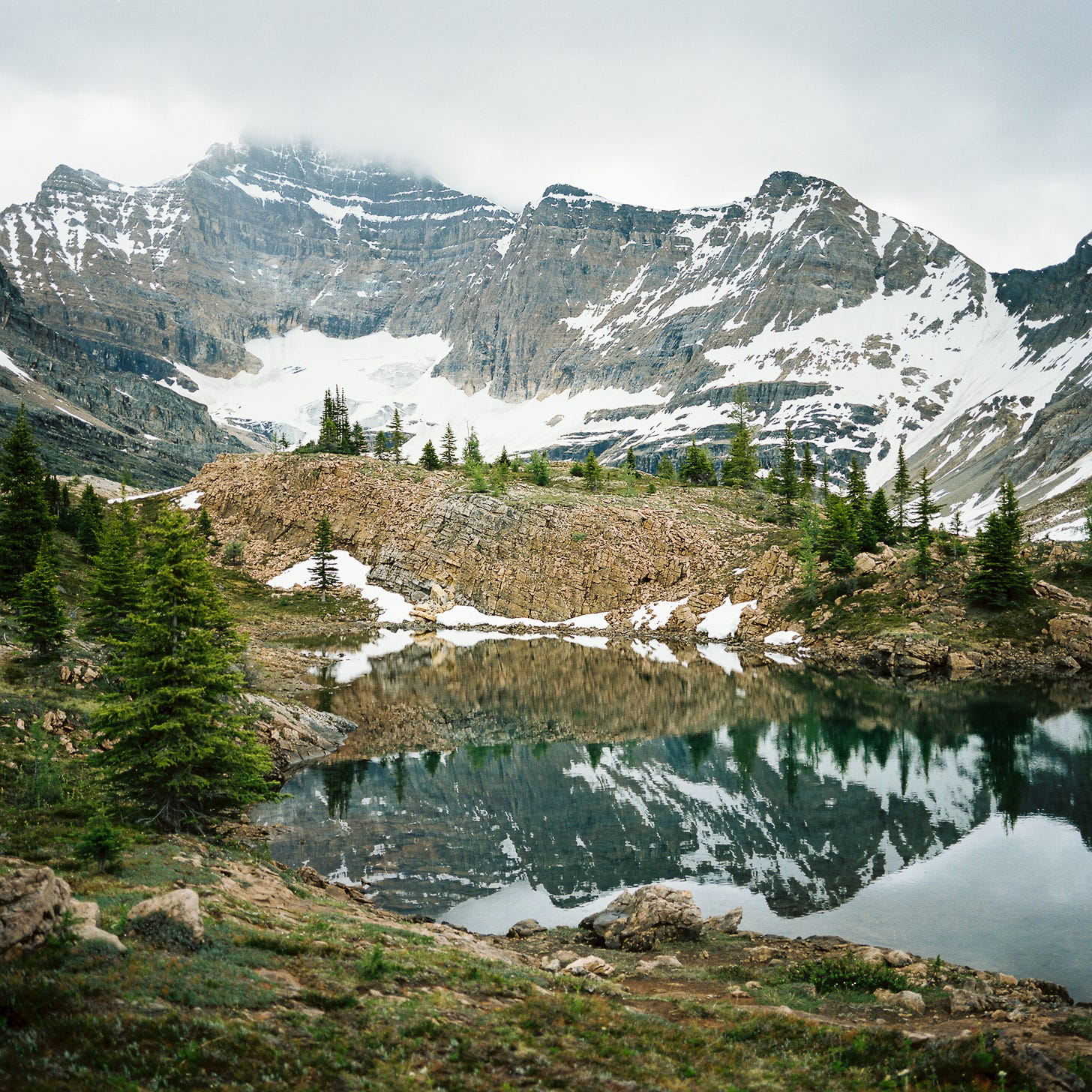 Photo of an alpine lake backed by snowy mountains