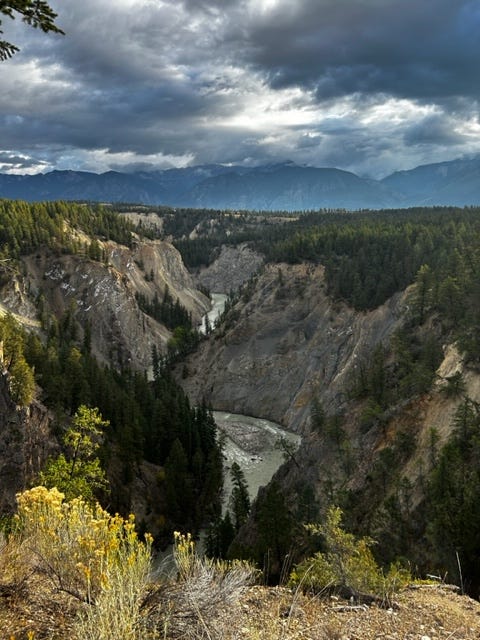 a river at the bottom of a beautiful canyon, contrasted against a cloudy sky