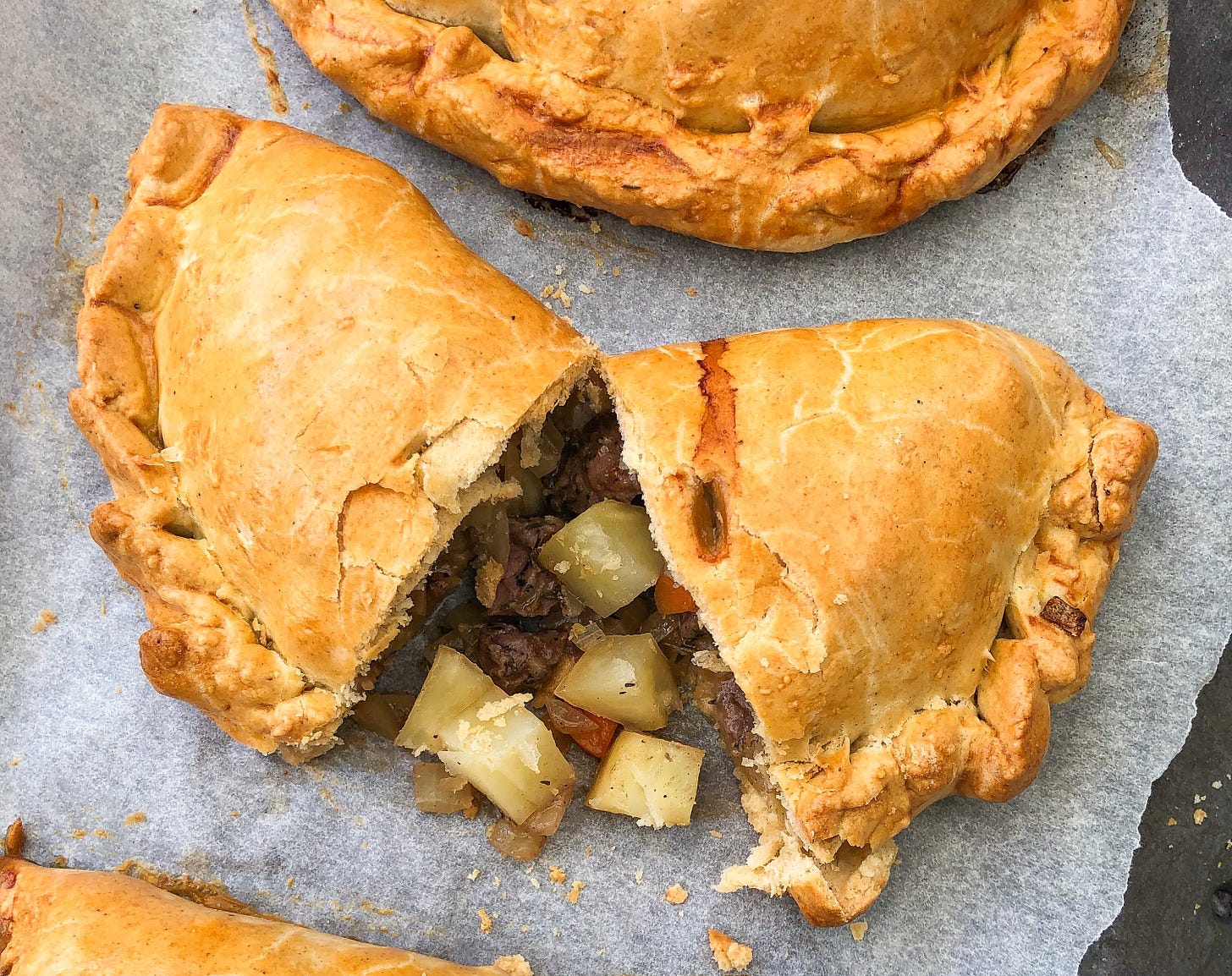 Meat and potato pie cut in two on greasproof paper