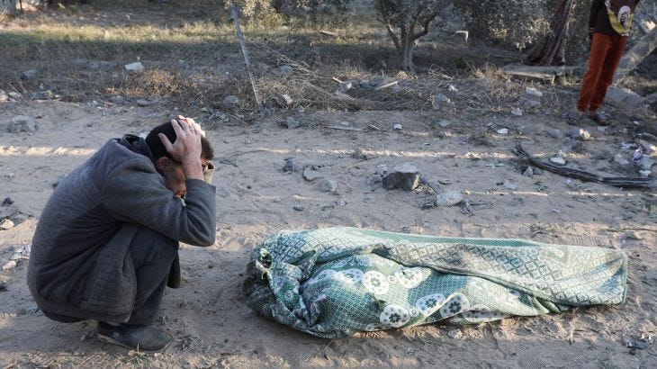 A person reacts next to a body, in the aftermath of an Israeli strike on a house, amid the Israel-Hamas conflict , in Deir Al-Balah, in the central Gaza Strip, December 22