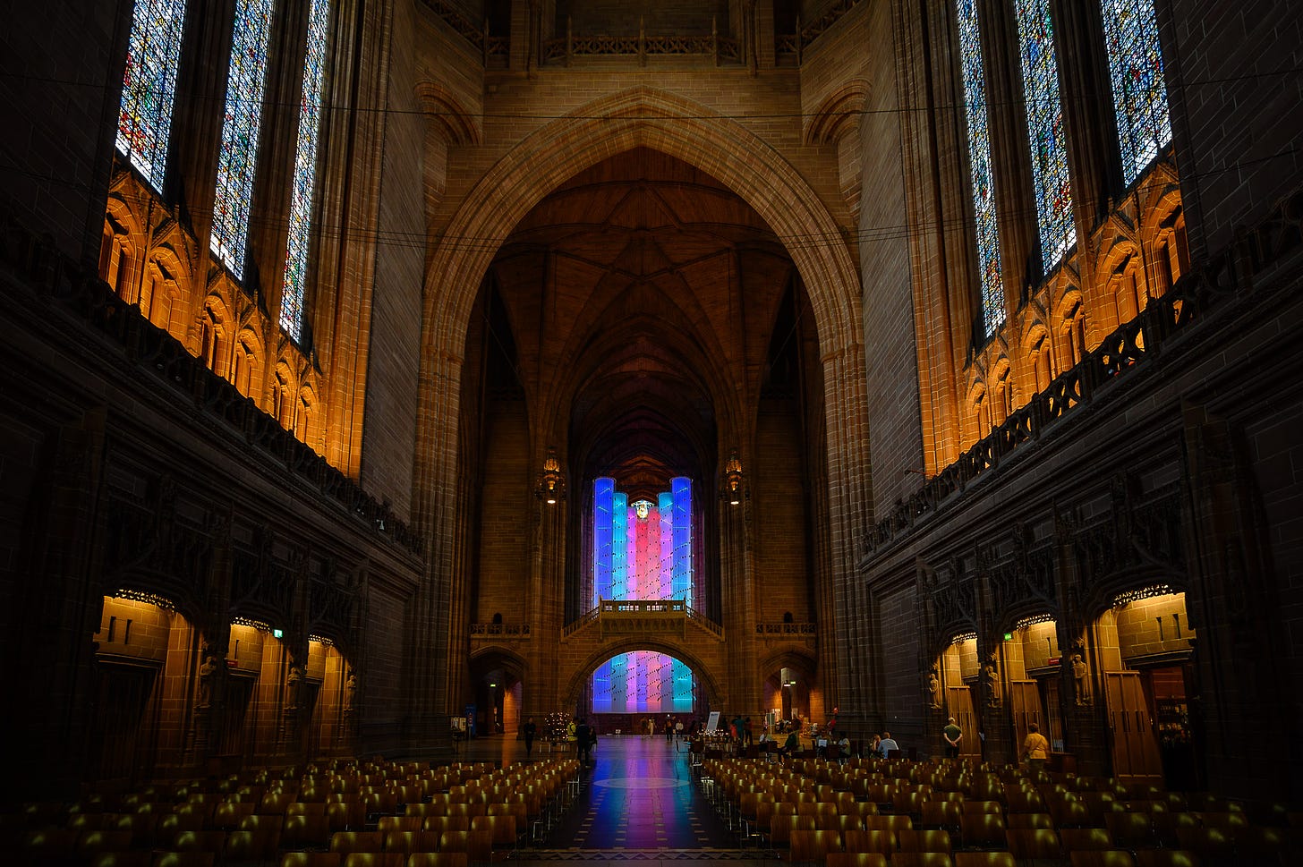 Inside a large cathedral space hangs columns of rainbow coloured light.