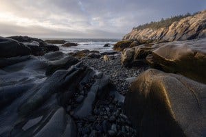 The day’s first light falls on one of the dramatic coastal beaches of Isle au Haut, Acadia National Park, Maine.
