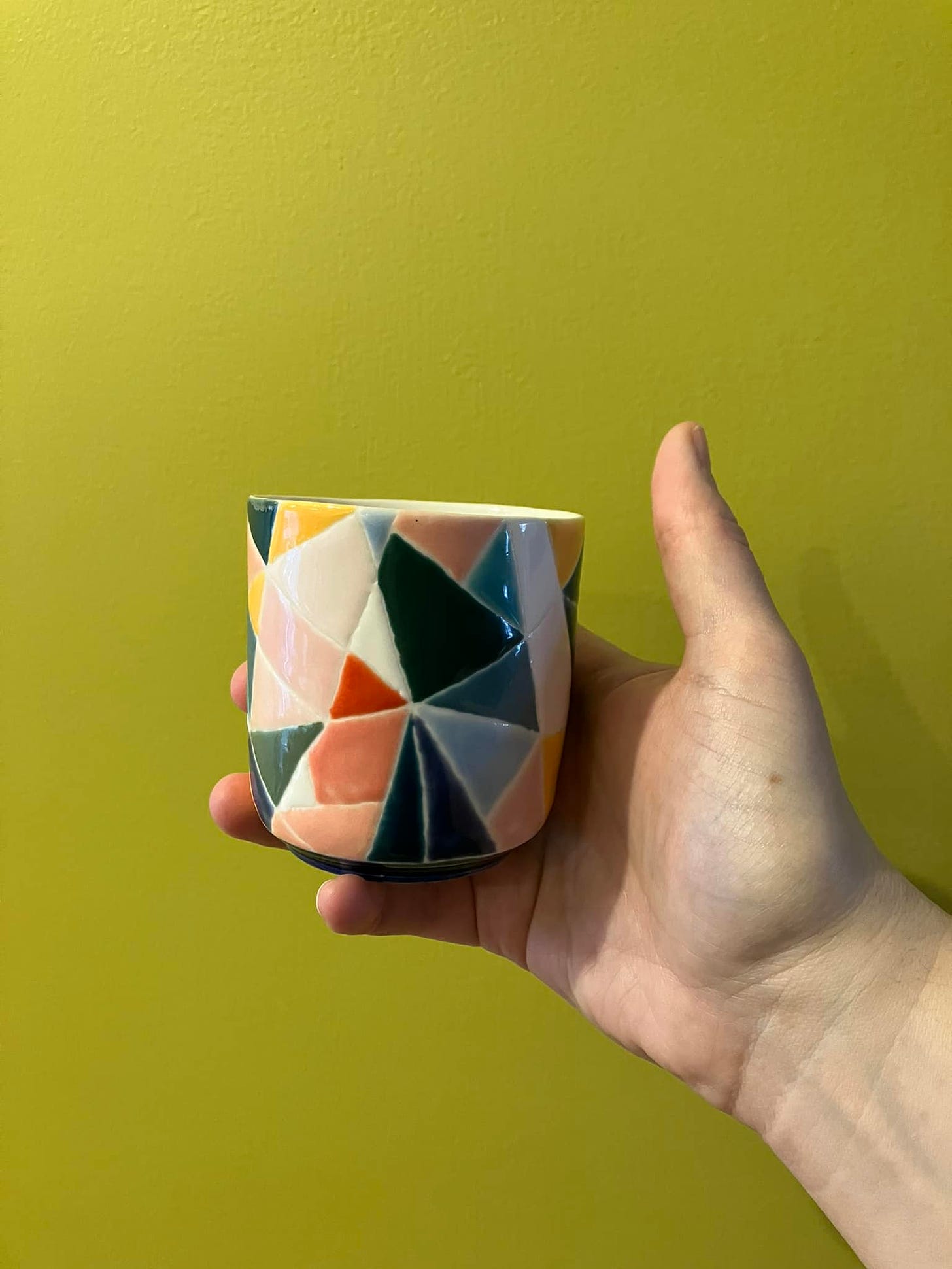 cup with multicolored triangles against a chartreuse background