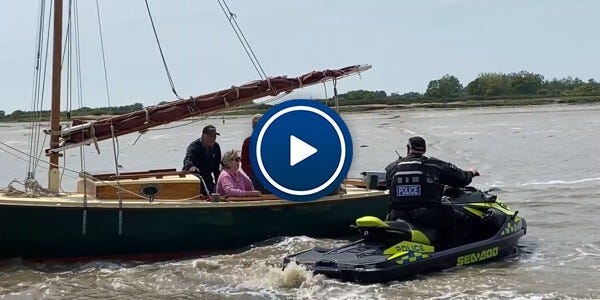 Police watercraft rider alongside people on a boat