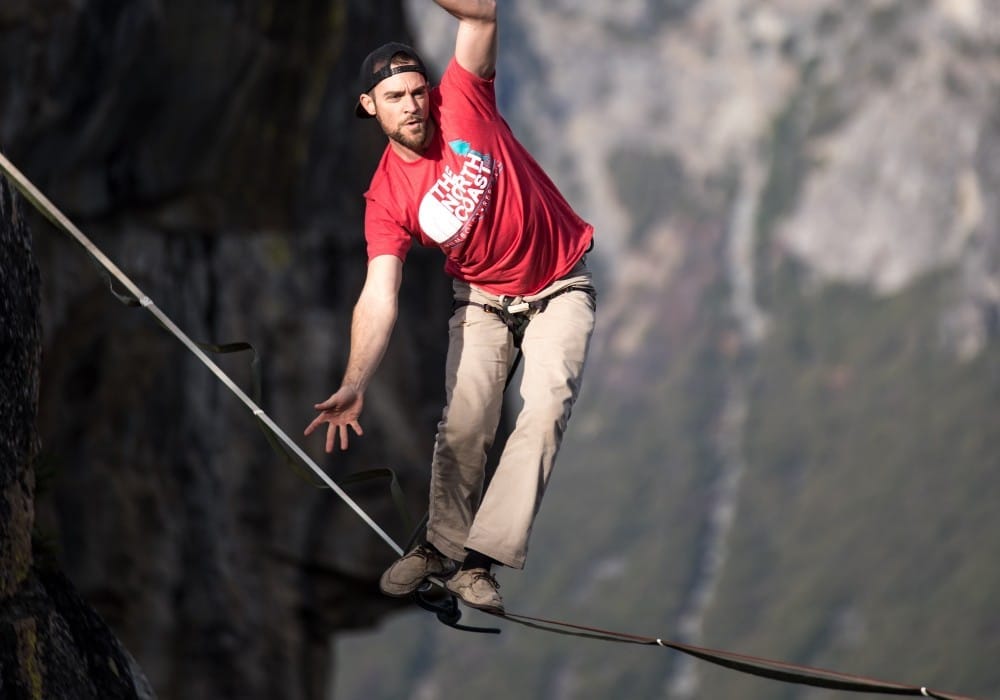 Rock climber with incredible balance on tight rope between two cliffs